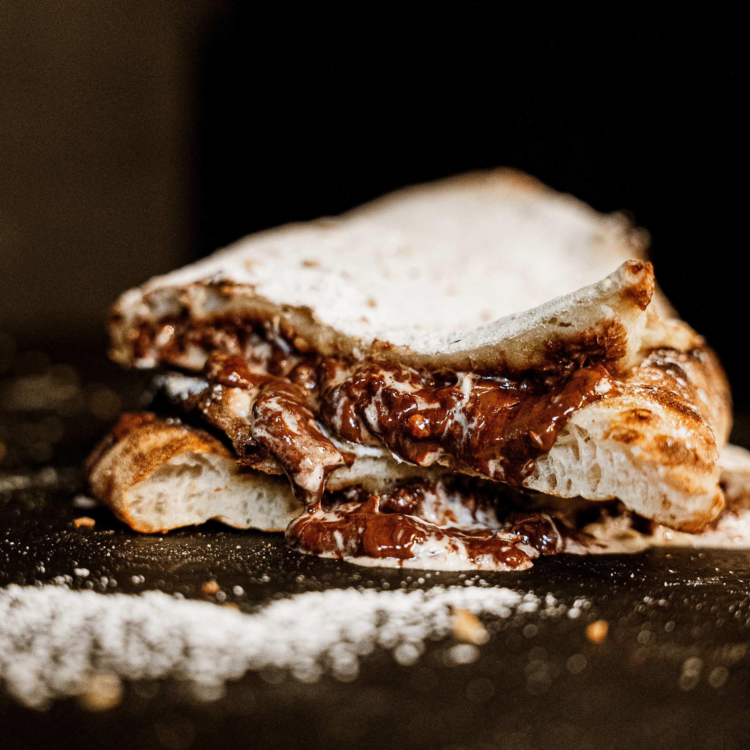 Gefaltete Teigtasche mit Schokoladencreme und Puderzucker auf Schiefer